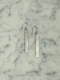 Silver bar earrings on a marble surface
