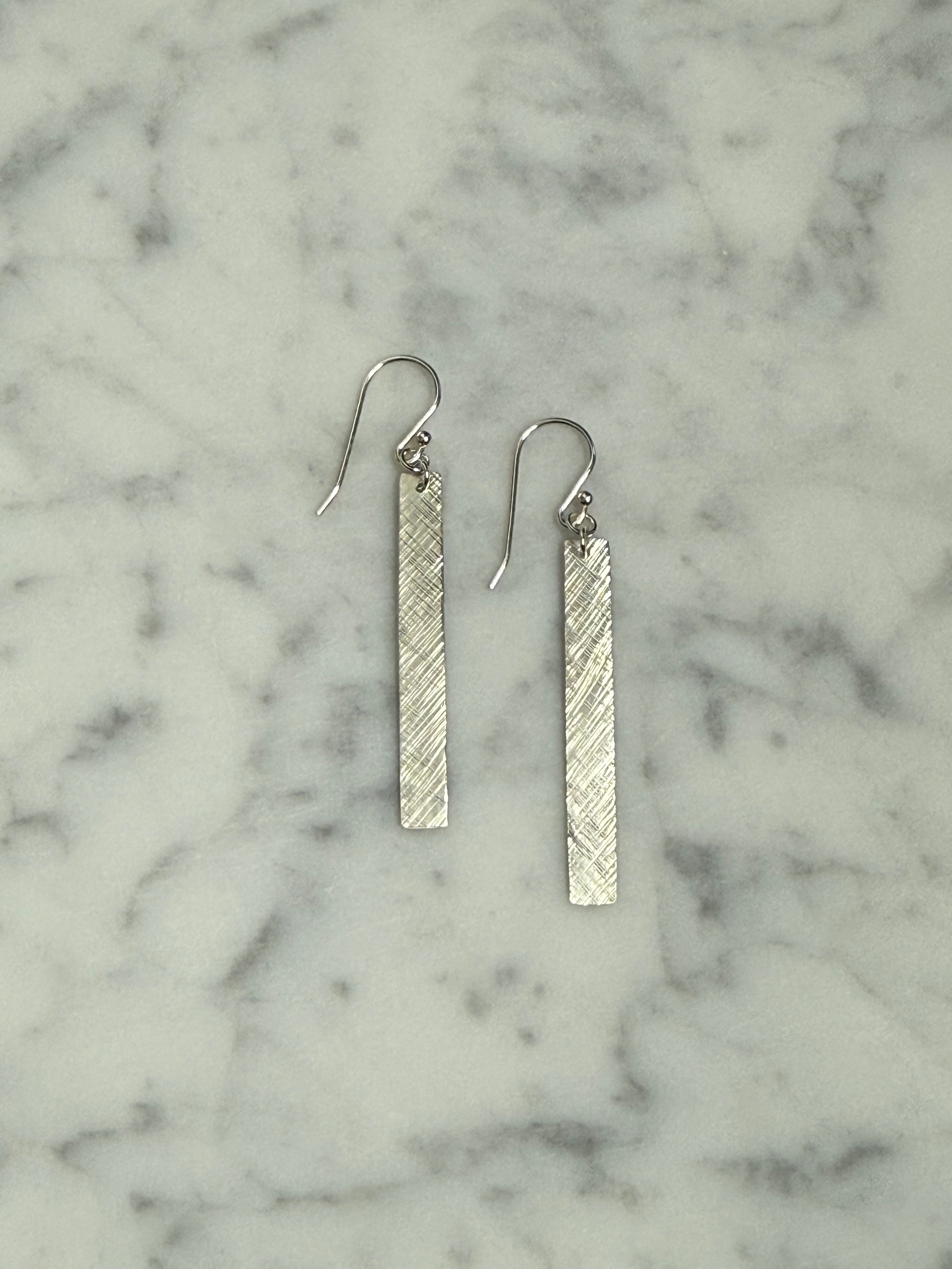 Silver bar earrings on a marble surface