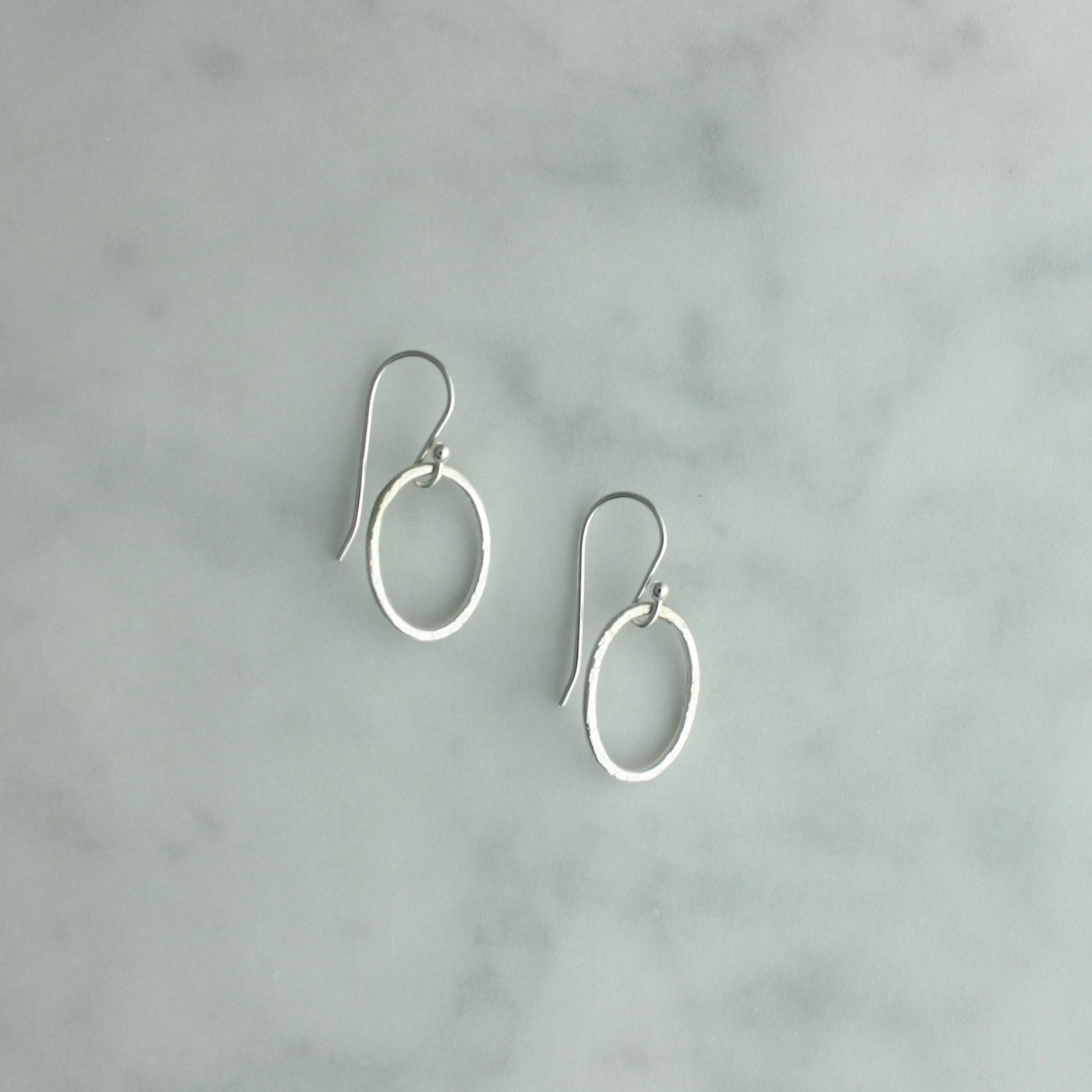 Pair of silver hoop earrings on a gray marble background