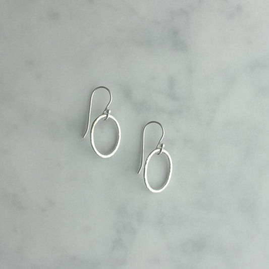 Pair of silver hoop earrings on a gray marble background