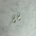 Pair of silver teardrop earrings on a marble surface