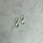 Pair of silver teardrop earrings on a marble surface